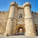 A medieval stone castle with cylindrical towers, an arched entrance and intricate stone detailing